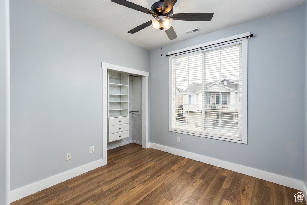 Unfurnished bedroom with ceiling fan, visible vents, baseboards, a closet, and dark wood-style floors