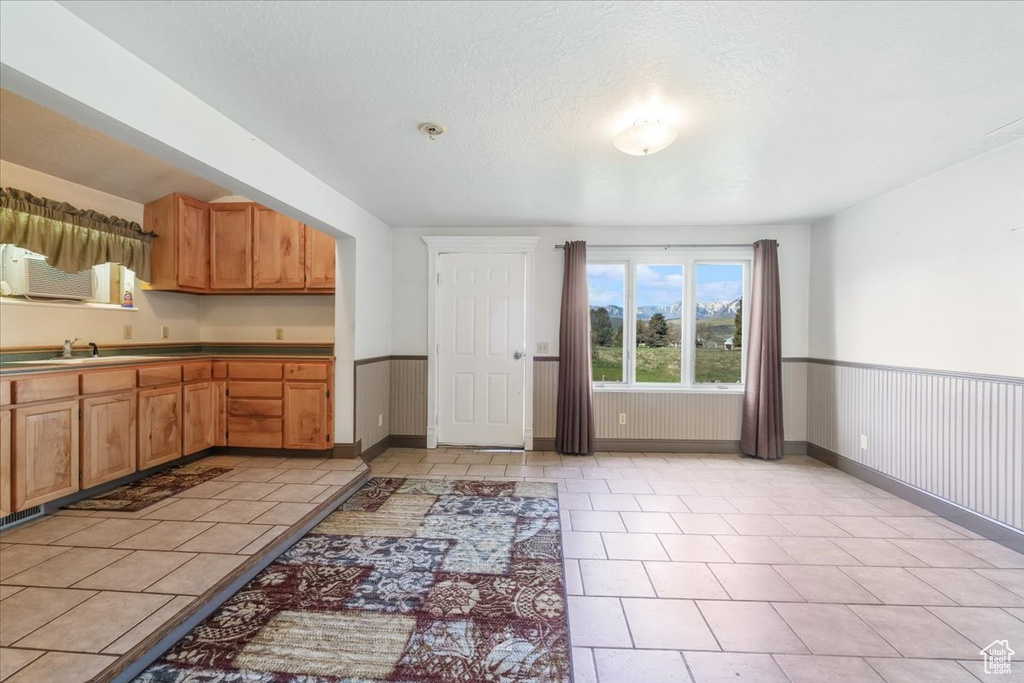 Kitchen featuring a sink, baseboards, light tile patterned floors, and wainscoting