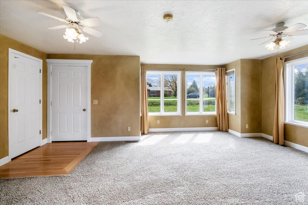 Carpeted empty room featuring baseboards, ceiling fan, and a textured ceiling