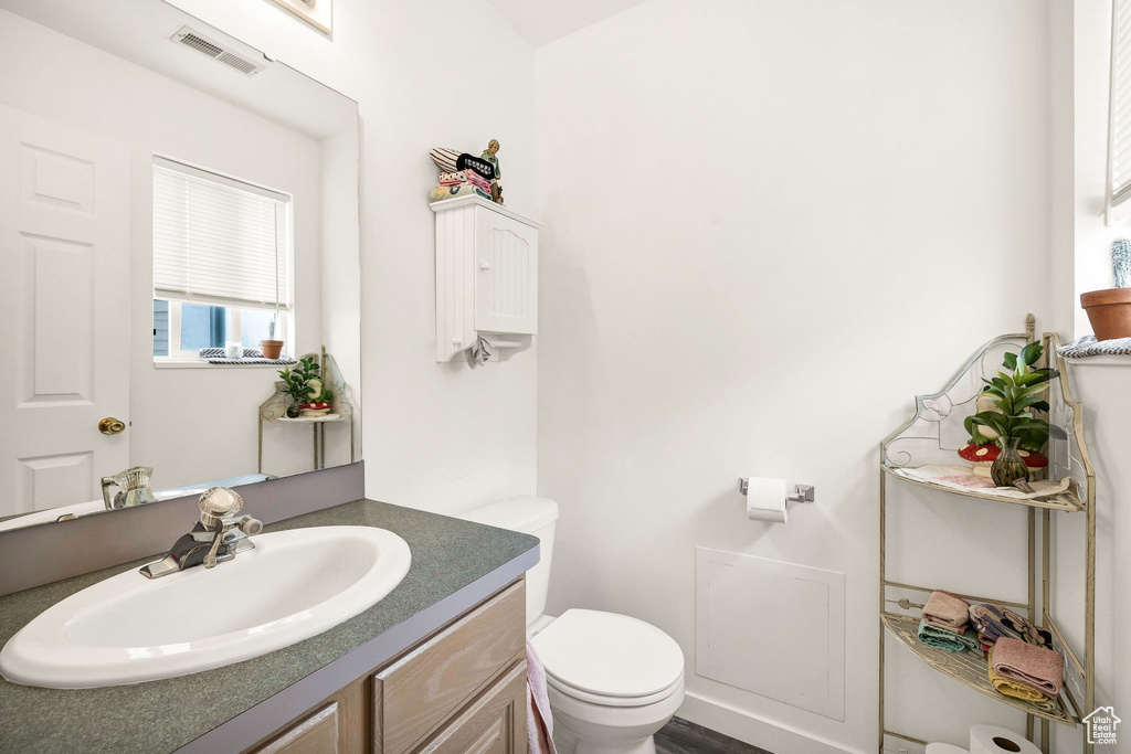 Half bathroom featuring visible vents, toilet, and vanity