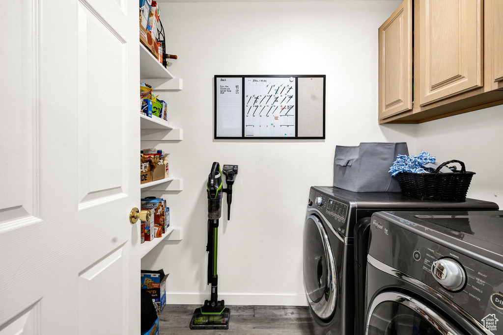 Clothes washing area with baseboards, washing machine and dryer, cabinet space, and wood finished floors