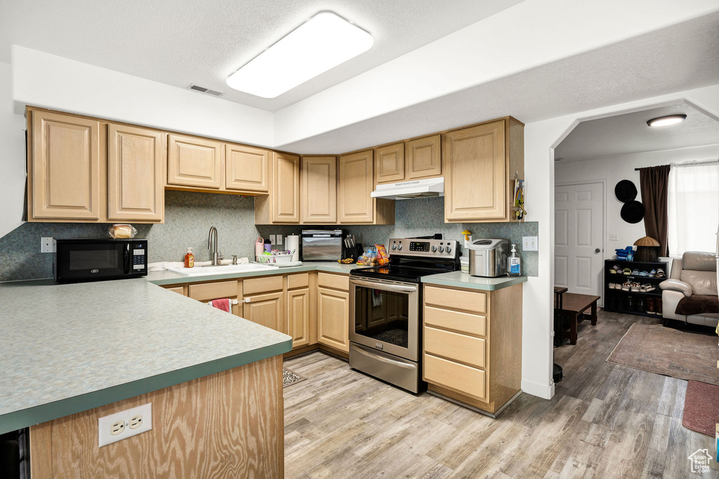 Kitchen featuring black microwave, a sink, light brown cabinets, under cabinet range hood, and stainless steel electric stove