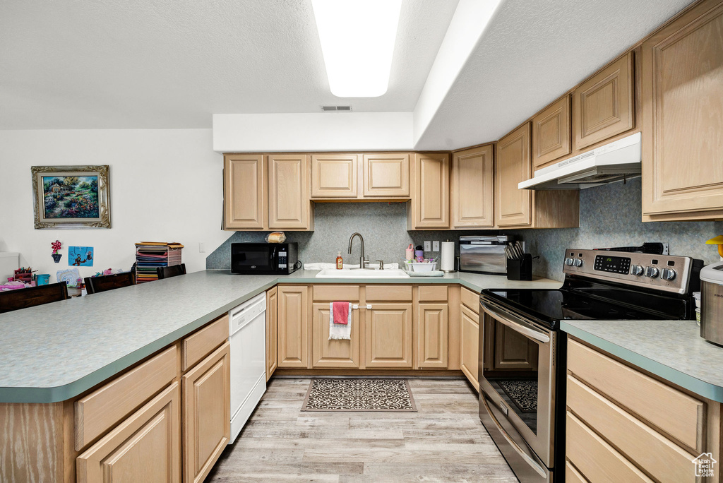 Kitchen featuring black microwave, light brown cabinetry, dishwasher, stainless steel range with electric stovetop, and under cabinet range hood