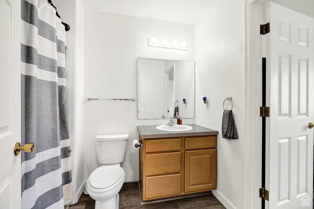 Full bath with toilet, baseboards, wood finished floors, and vanity