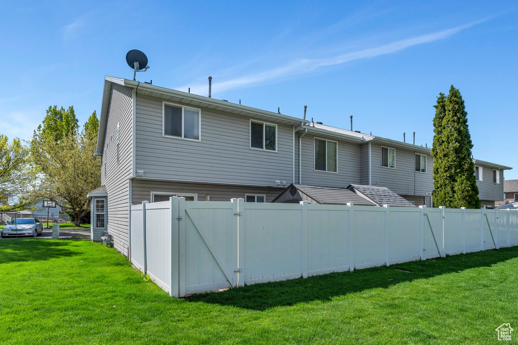 Back of property with a lawn, fence, and a gate