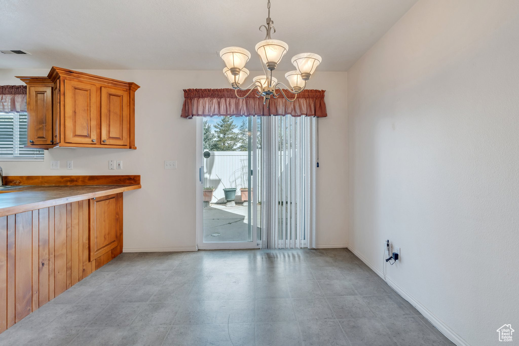 Unfurnished dining area featuring baseboards, visible vents, and a notable chandelier