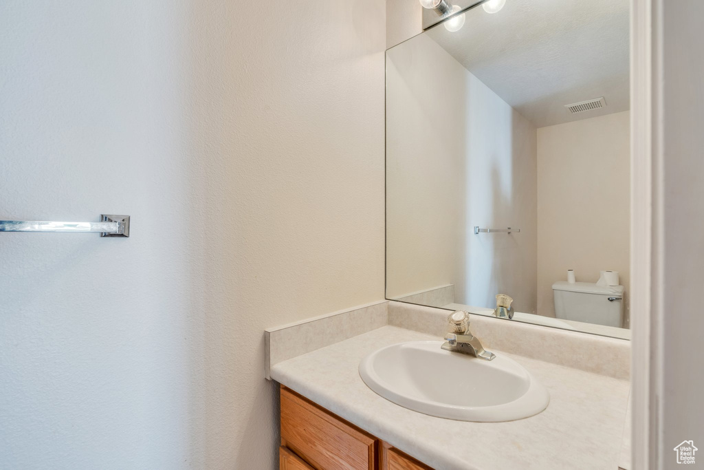 Half bathroom with toilet, visible vents, and vanity