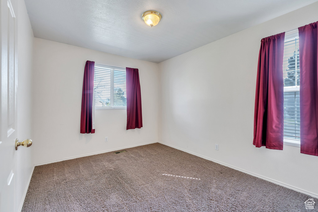 Carpeted empty room with baseboards and visible vents