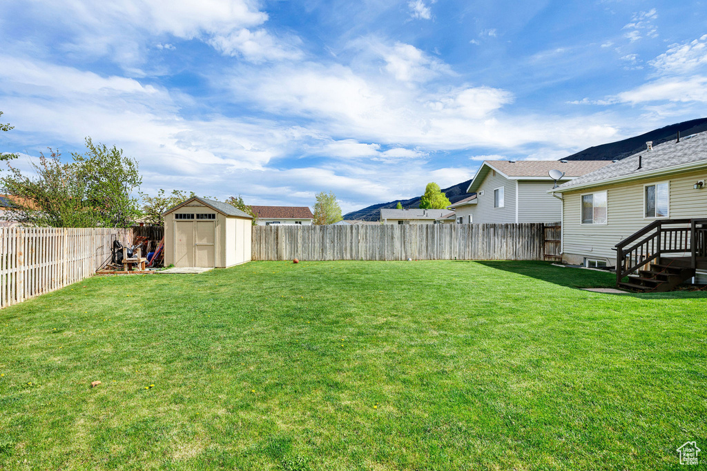 View of yard with a fenced backyard, a storage unit, and an outbuilding