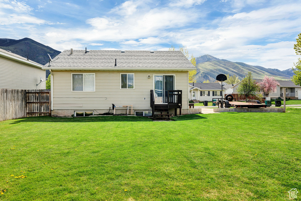 Back of house with a lawn, fence, and a mountain view