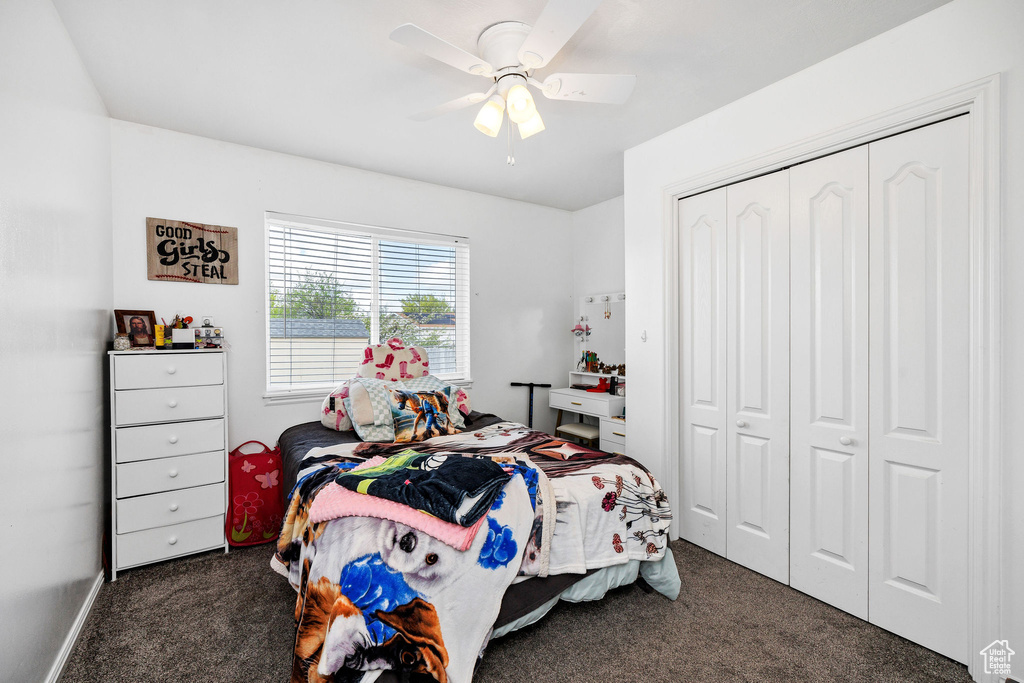 Bedroom with a ceiling fan, dark carpet, and a closet