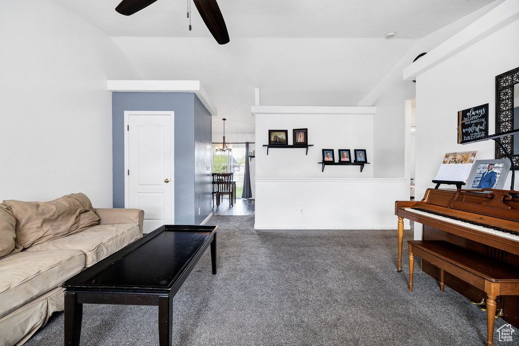Living room with carpet flooring, ceiling fan with notable chandelier, and lofted ceiling
