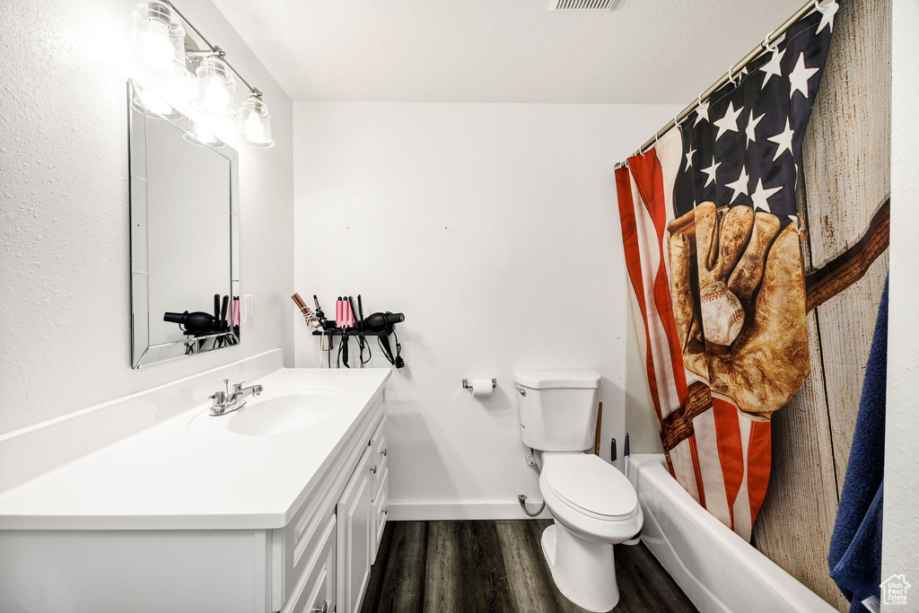 Bathroom with vanity, toilet, baseboards, wood finished floors, and visible vents