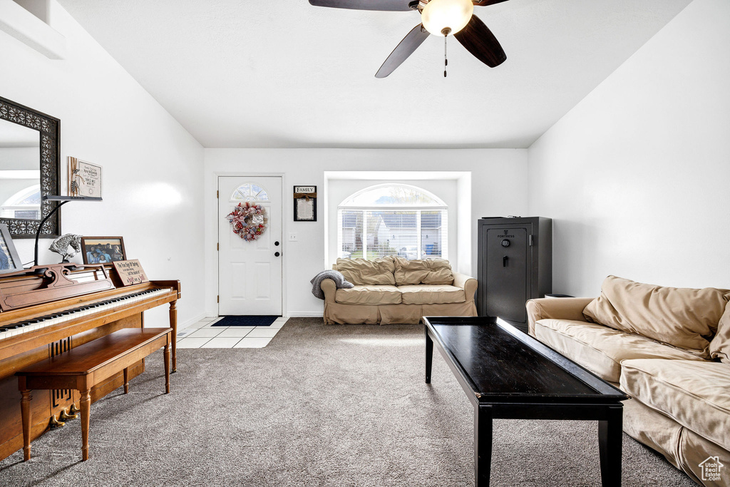 Living area featuring a ceiling fan, light carpet, light tile patterned flooring, and lofted ceiling