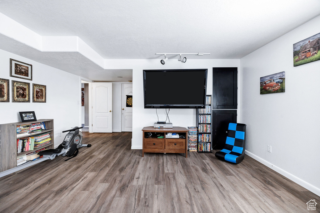 Living room featuring baseboards, rail lighting, and wood finished floors