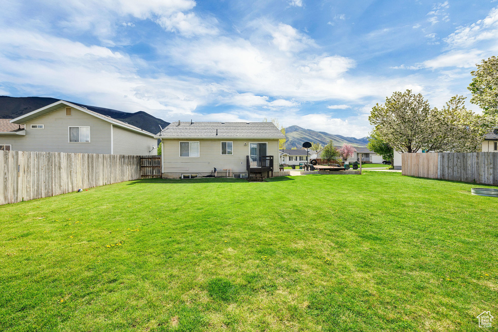 Rear view of house featuring a yard, fence, and a mountain view