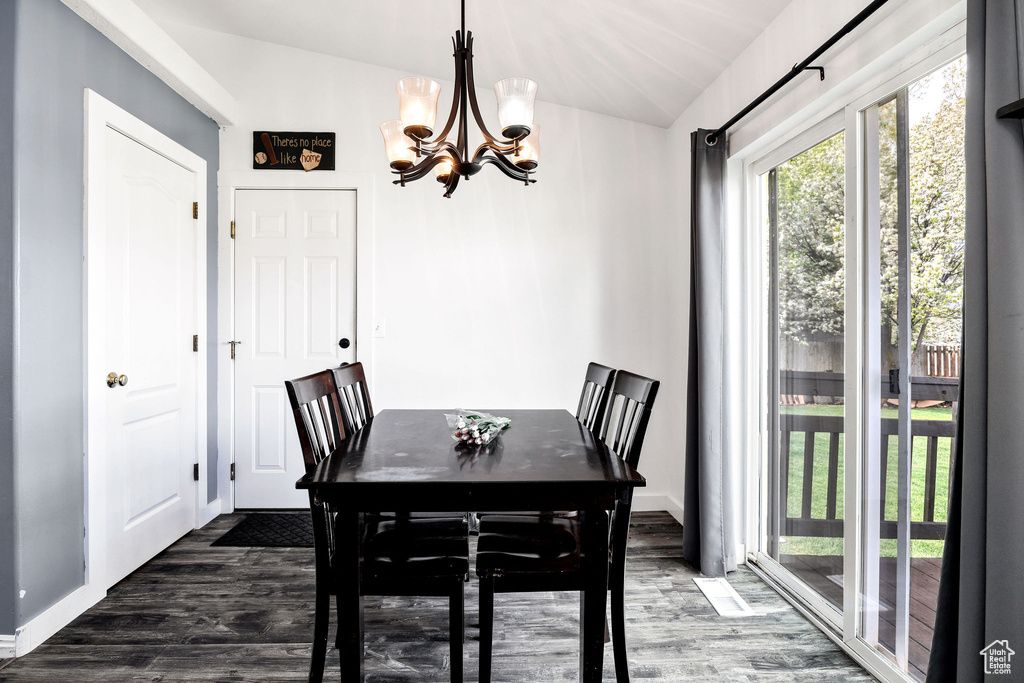 Dining space featuring an inviting chandelier, vaulted ceiling, and wood finished floors
