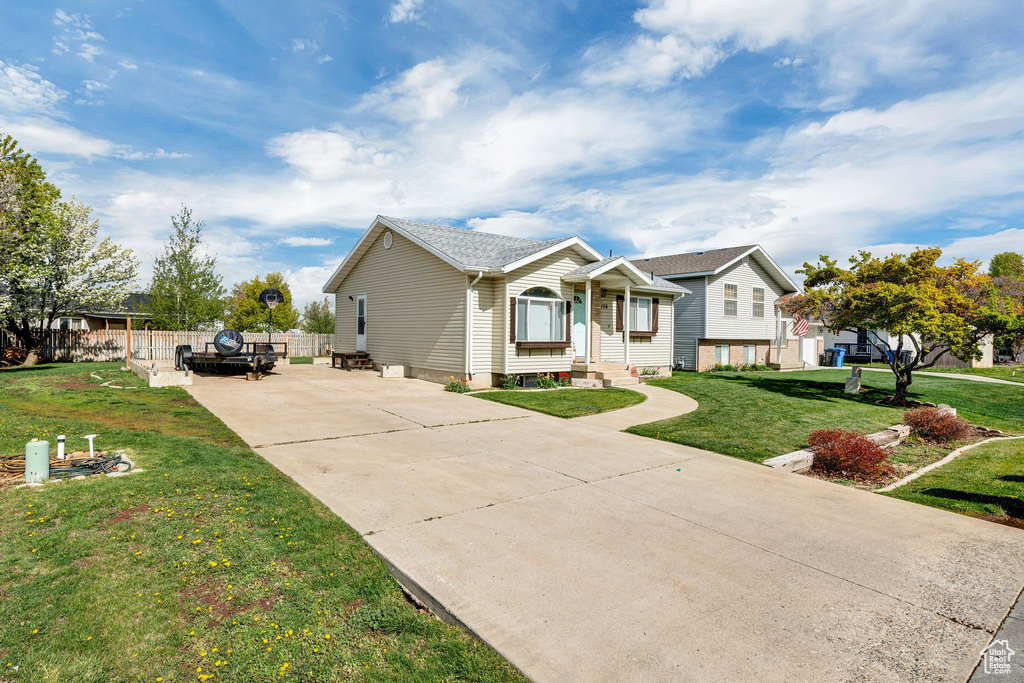 Ranch-style home with concrete driveway, fence, and a front yard