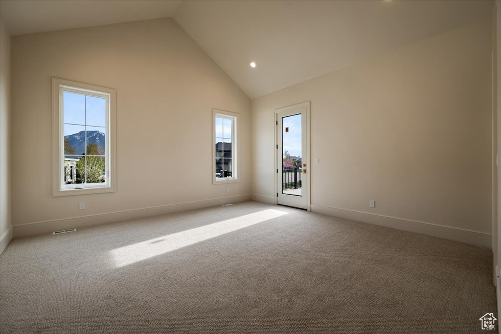Unfurnished room with baseboards, carpet flooring, visible vents, and high vaulted ceiling