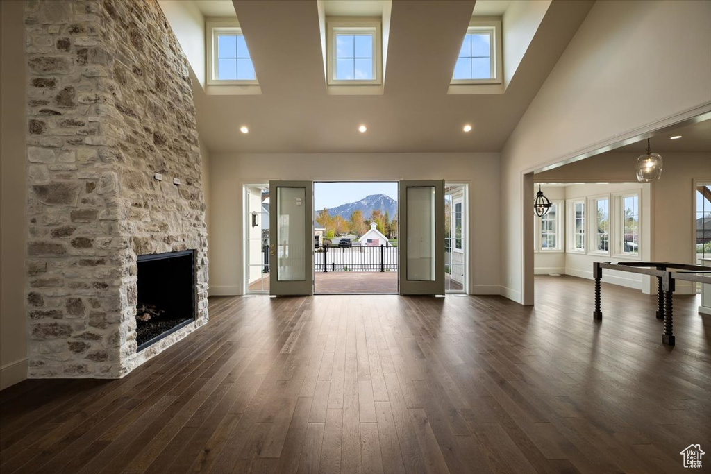 Unfurnished living room with a high ceiling, a fireplace, and dark wood-style flooring