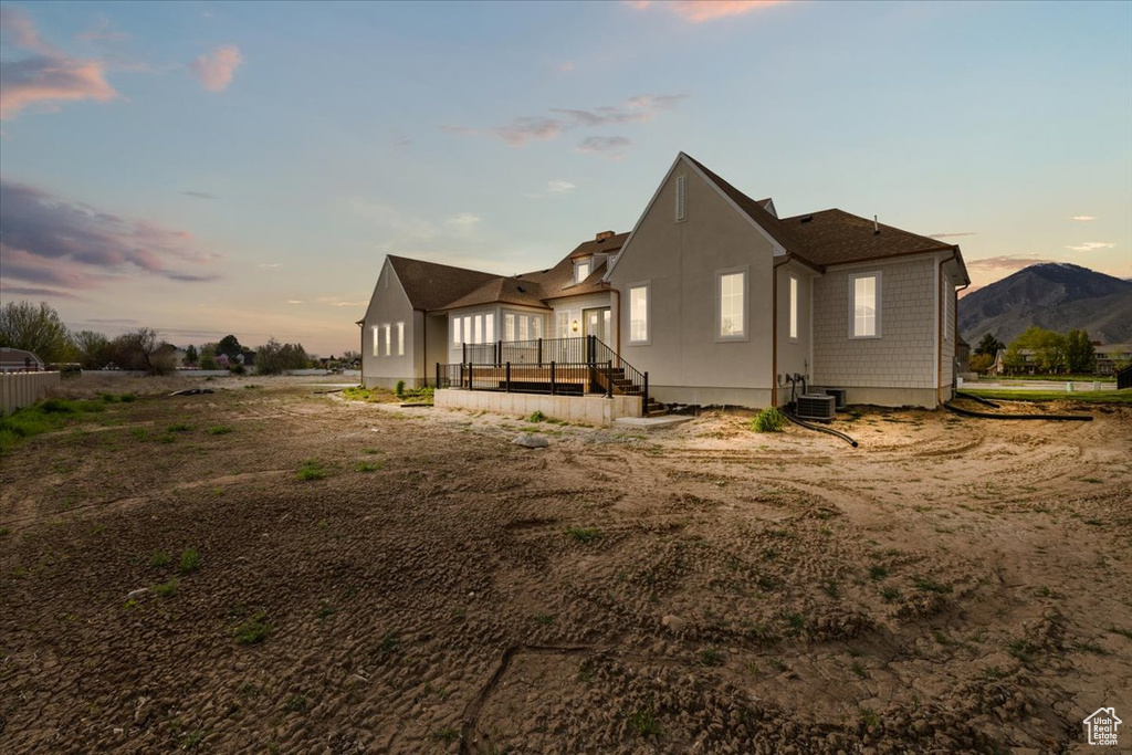 Back of house at dusk with central air condition unit and a wooden deck