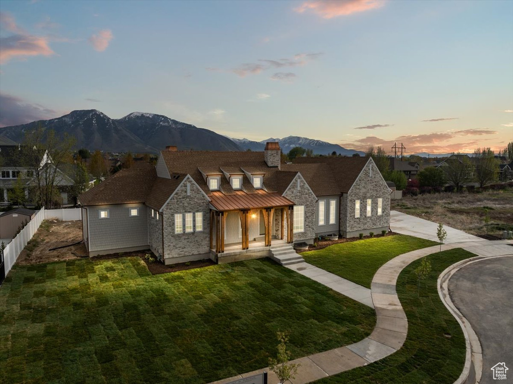 View of front of house featuring a chimney, fence, a mountain view, a yard, and stone siding