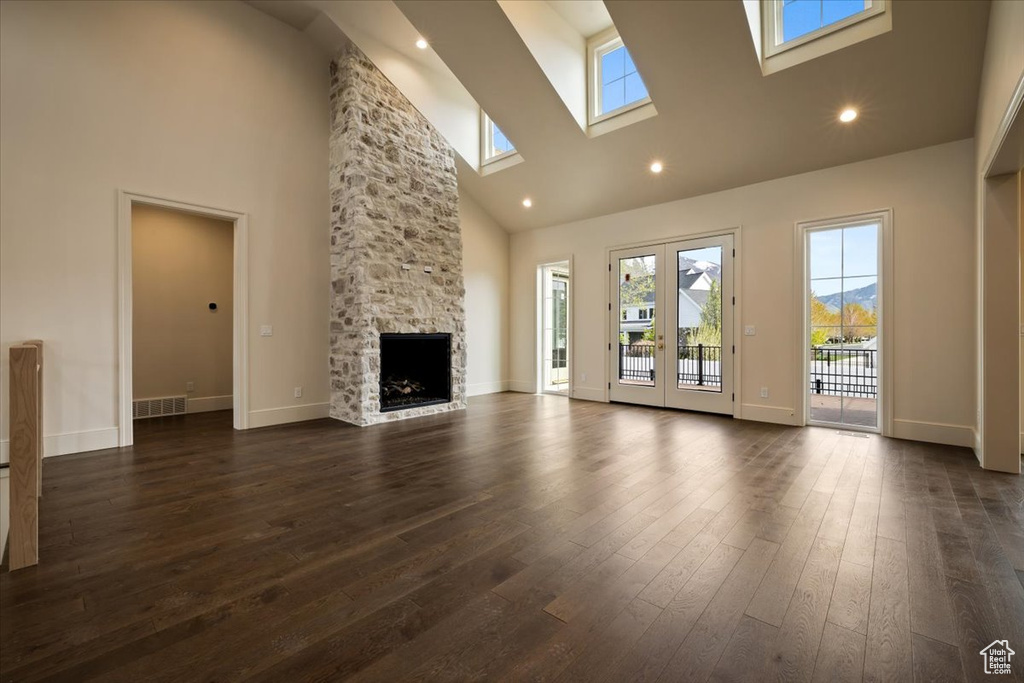 Unfurnished living room with a skylight, high vaulted ceiling, dark wood-type flooring, and a wealth of natural light