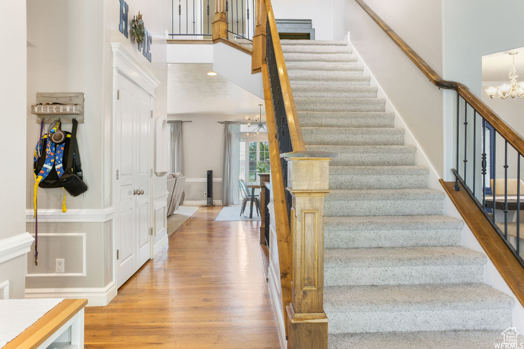 Stairs featuring baseboards, wood finished floors, and a notable chandelier