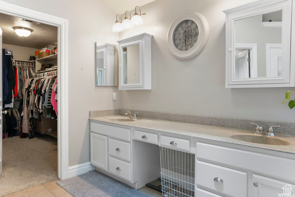 Bathroom with a sink, tile patterned flooring, double vanity, and a spacious closet