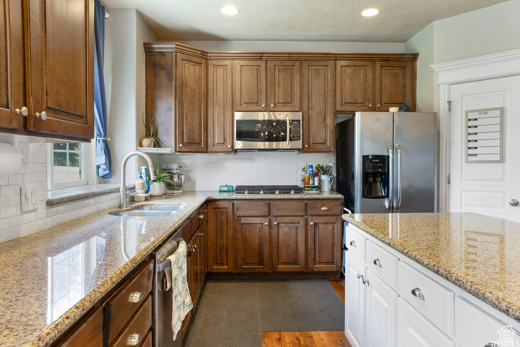 Kitchen with white cabinets, backsplash, appliances with stainless steel finishes, and a sink