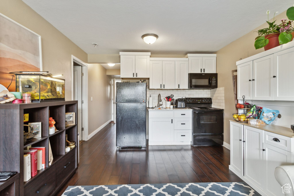 Kitchen featuring baseboards, a sink, black appliances, and tasteful backsplash
