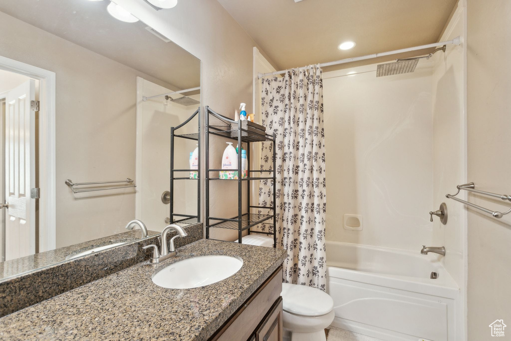Bathroom with vanity, shower / bathtub combination with curtain, visible vents, and toilet