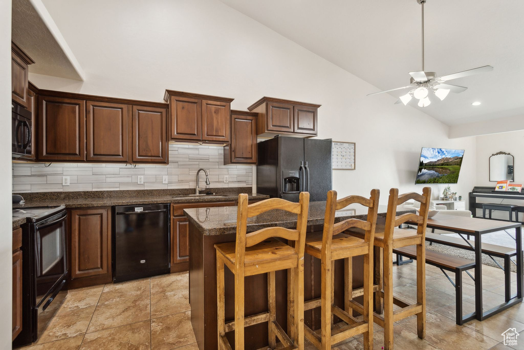 Kitchen featuring decorative backsplash, a kitchen island, ceiling fan, a sink, and black appliances