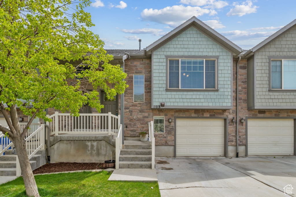 Multi unit property with an attached garage, driveway, and stone siding