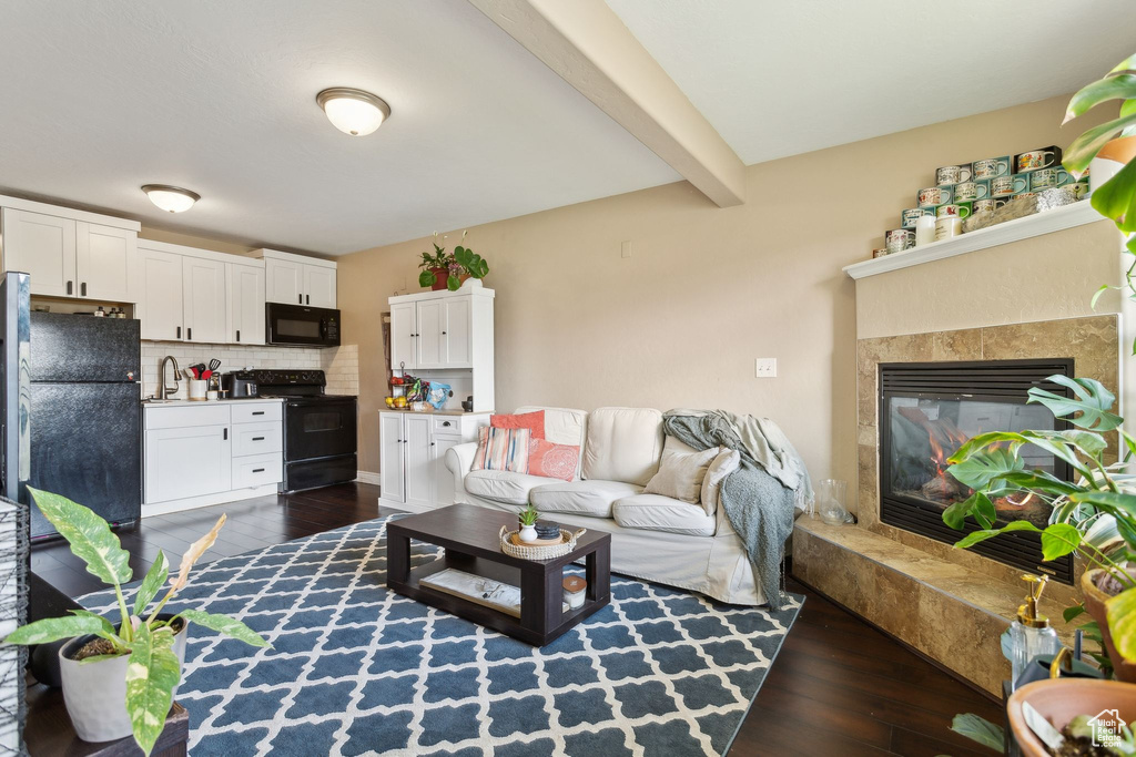 Living area featuring beamed ceiling, a glass covered fireplace, and dark wood-style floors