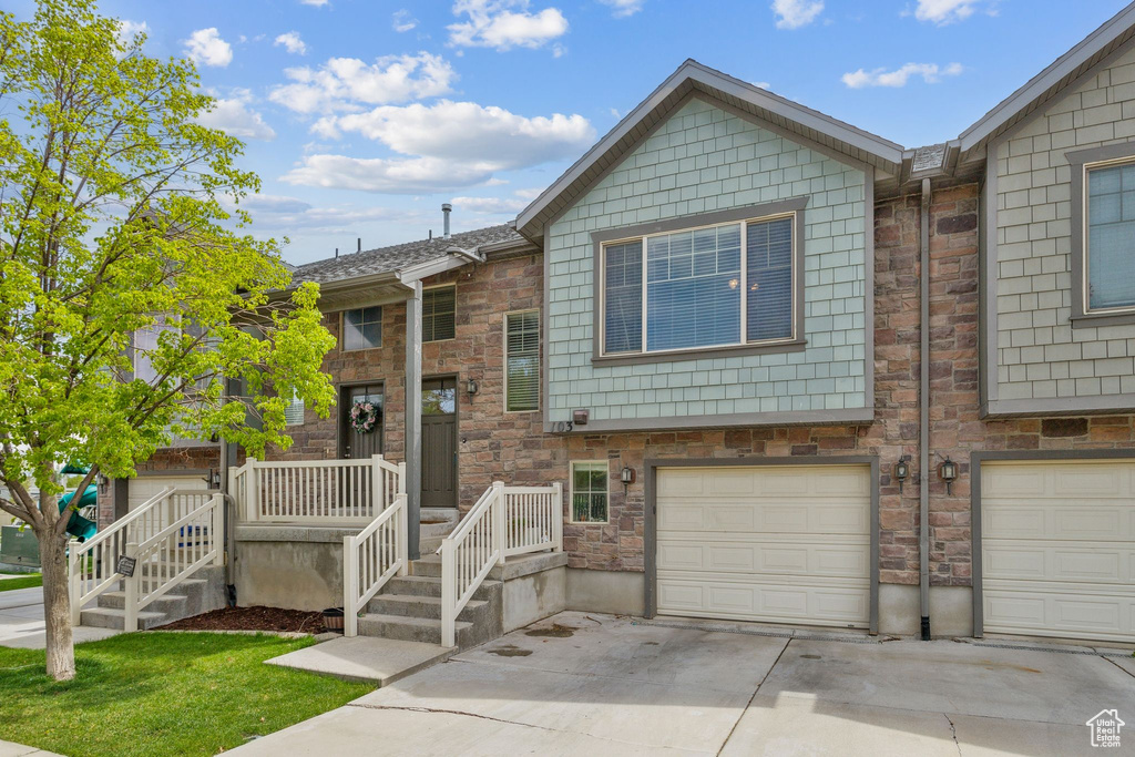 View of property featuring an attached garage, driveway, and stone siding