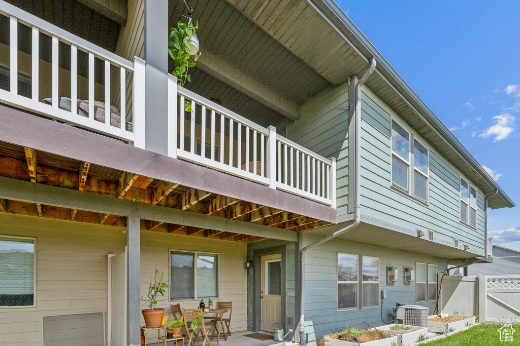 Exterior space featuring fence, central AC unit, a patio area, and a balcony