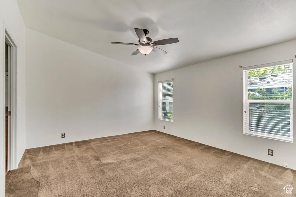 Unfurnished room with plenty of natural light, carpet flooring, and a ceiling fan