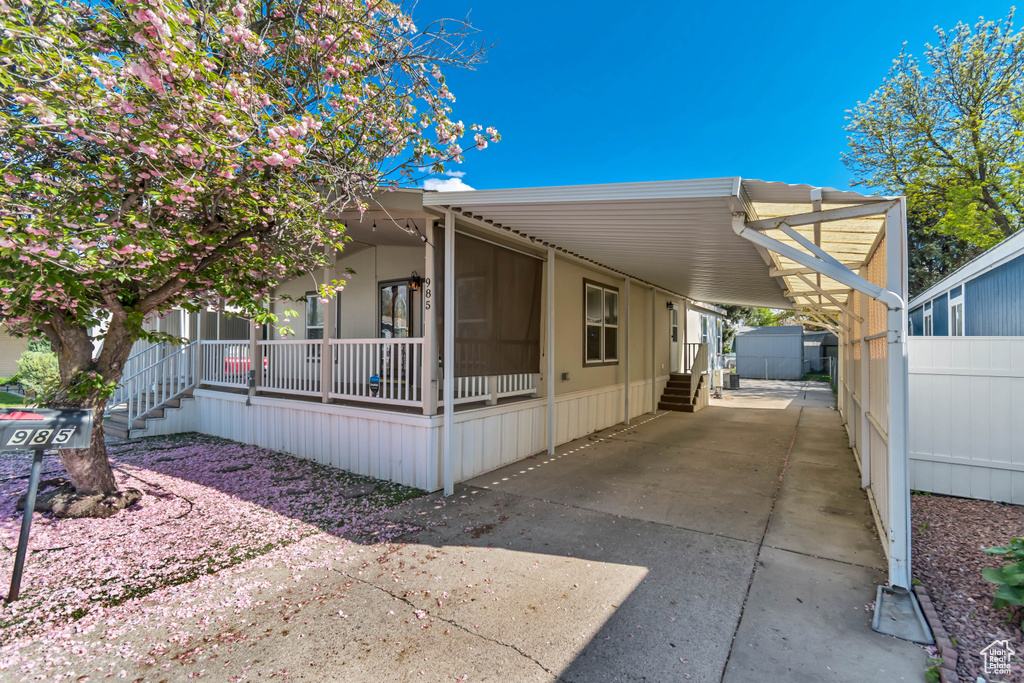 View of front of home featuring fence, a carport, concrete driveway, and a porch