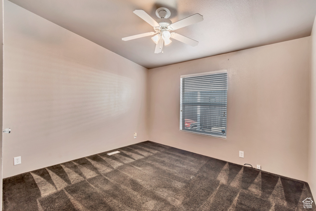 Unfurnished room with ceiling fan and dark carpet