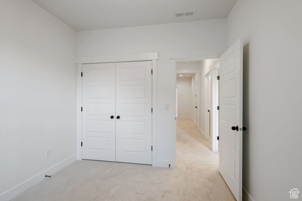 Unfurnished bedroom with visible vents, baseboards, a closet, and light colored carpet