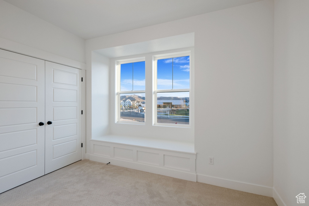 Unfurnished bedroom with light carpet and a closet