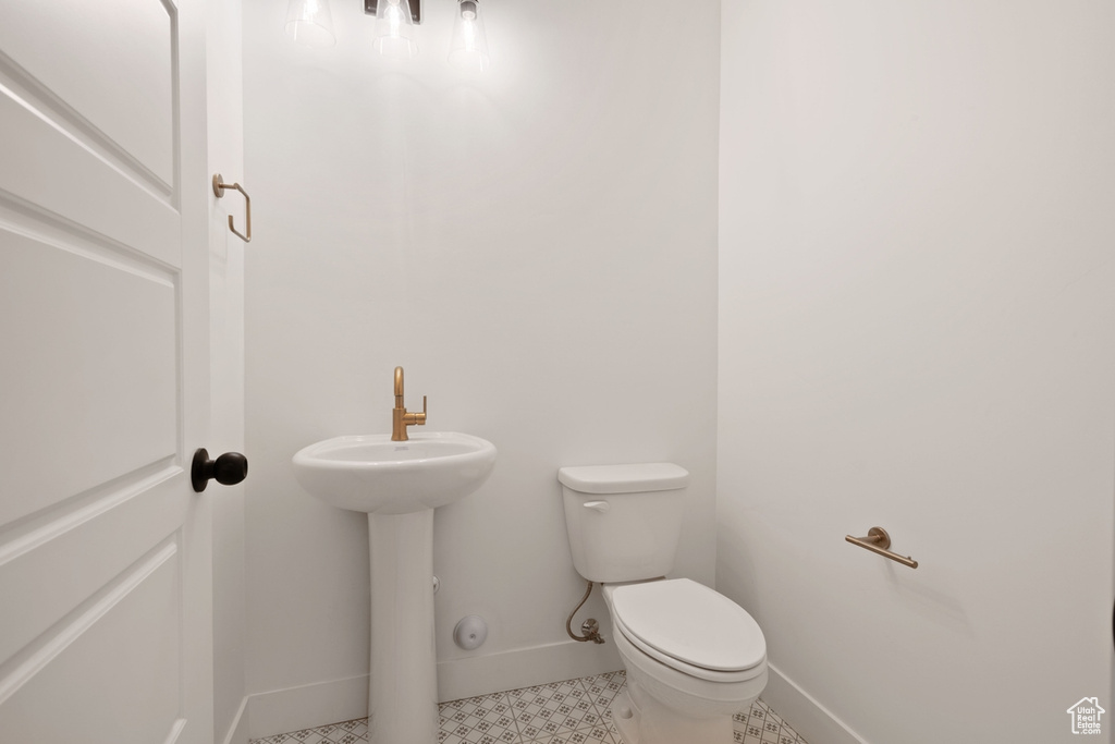 Half bathroom featuring baseboards, tile patterned flooring, and toilet
