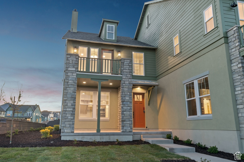 View of front of house with fence, a balcony, and stone siding