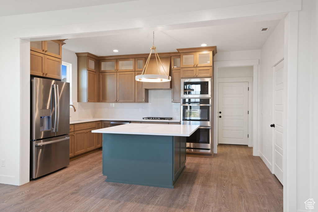 Kitchen featuring a center island, light countertops, appliances with stainless steel finishes, and wood finished floors