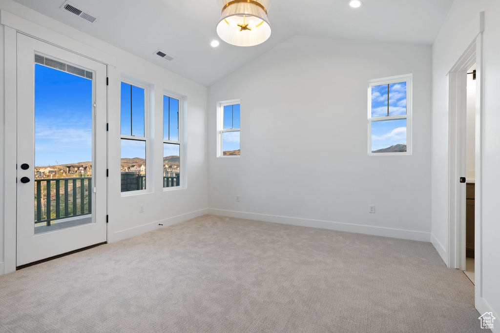 Unfurnished room featuring carpet, lofted ceiling, and visible vents
