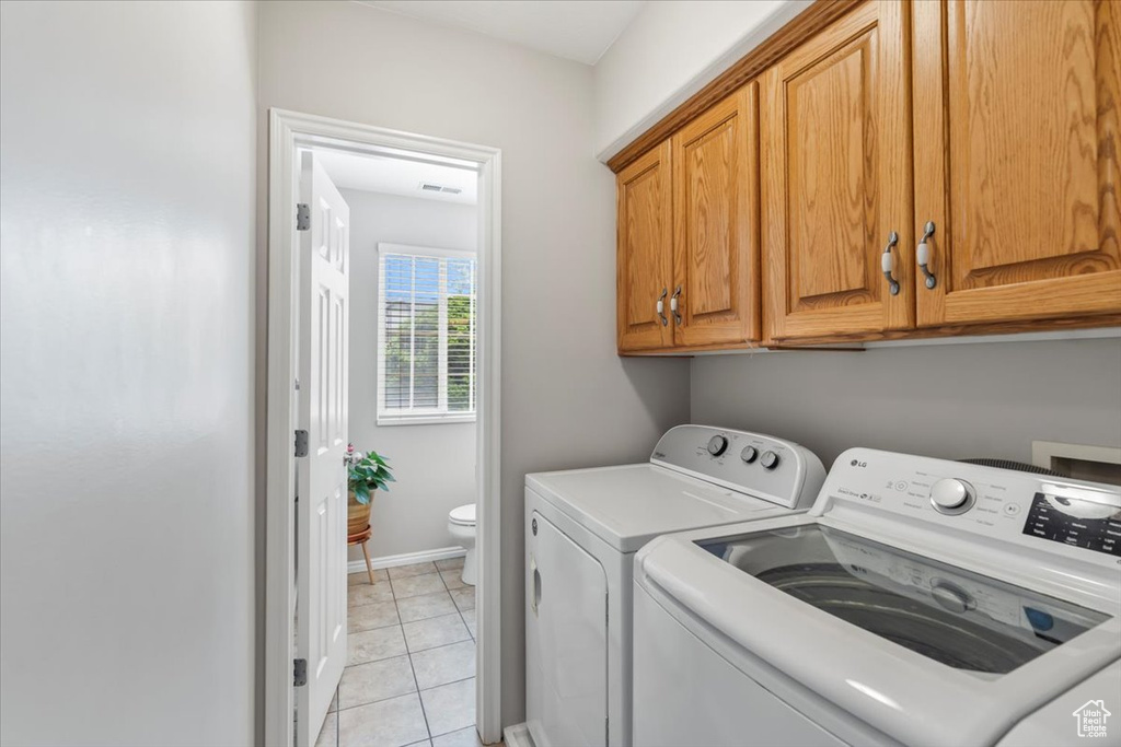 Washroom with washing machine and clothes dryer, cabinet space, baseboards, light tile patterned floors, and visible vents
