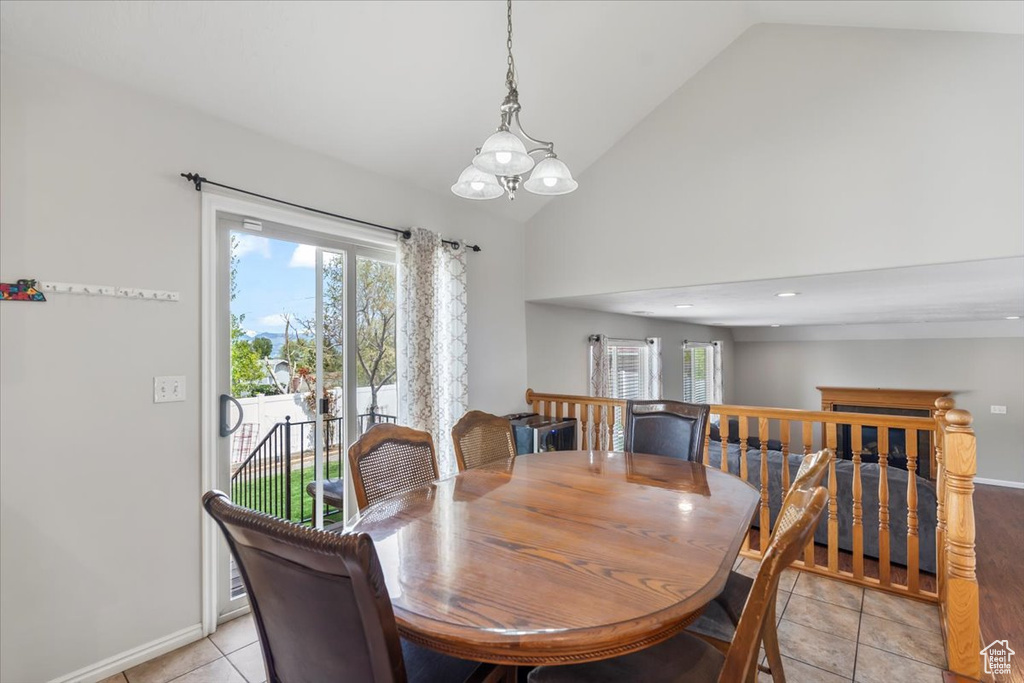 Dining space featuring light tile patterned floors, baseboards, high vaulted ceiling, and a notable chandelier