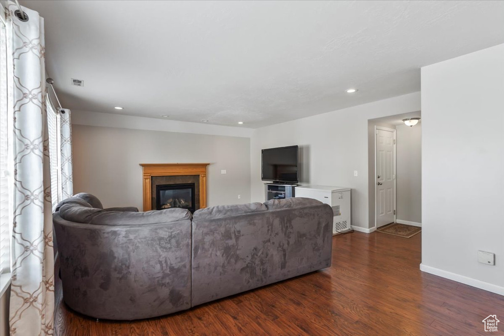 Living area with visible vents, a glass covered fireplace, wood finished floors, baseboards, and recessed lighting