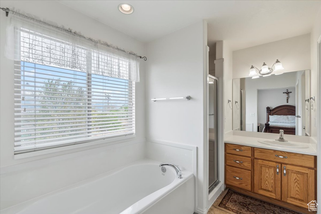 Ensuite bathroom with vanity, ensuite bathroom, a shower stall, and a garden tub